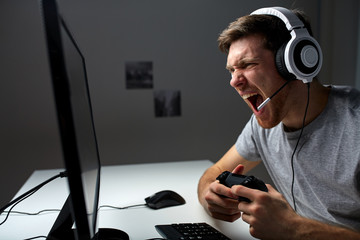 man in headset playing computer video game at home