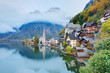 Early morning view of Hallstatt with reflections on smooth lake water, a lakeside village in Salzkammergut region of Austria, in the colorful autumn season