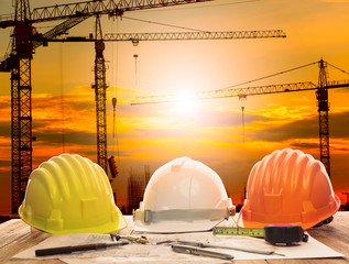 crane in construction site and working table of civil engineer with writing tool and plan of building