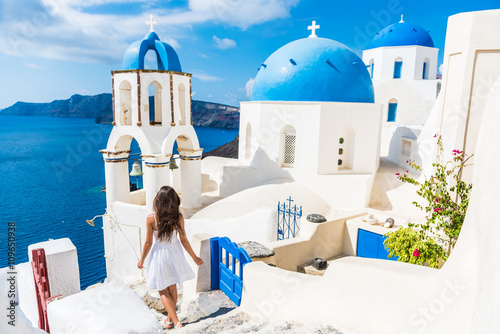 Fotografie, Obraz Santorini travel tourist woman on vacation in Oia walking on stairs