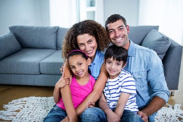 Wall Mural - Portrait of happy family sitting together on floor