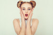Close-up portrait of surprised beautiful girl with funny hairstyle holding her head in amazement and open-mouthed. 