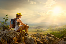 Portrait of woman with backpacker sitting on top of the mountain enjoying valley view