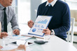 © DragonImages - Business person presenting financial report to his colleagues