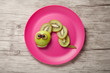 Caterpillar made of kiwi, apple and grape on plate