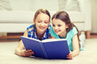 © Syda Productions - two happy girls reading book at home