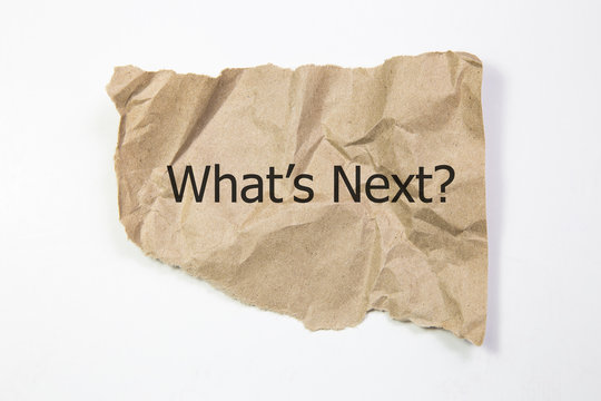 The motivational quote what's next appearing behind torn paper.