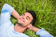 Leinwandbild Motiv Beautiful young man with closed eyes, dreaming and relax on the green grass