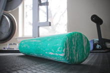 Green workout foam roller on gym floor