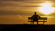 © icsnaps - Portrait of a silhouette man sitting on a bench looking towards the sunset, with copy space