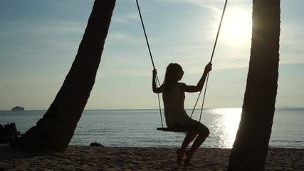 Poster - Young woman on a swing at the tropical beach against the sea