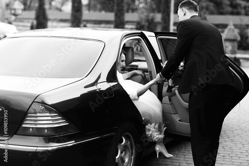 Pinturas sobre lienzo  Groom helps bride to go out of the black Mercedes