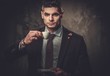 © Nejron Photo - Serious well-dressed hispanic man with cup of coffee posing on dark background.