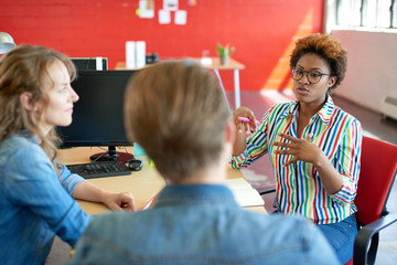 Wall Mural - Unposed group of creative business people in an open concept office brainstorming their next project.