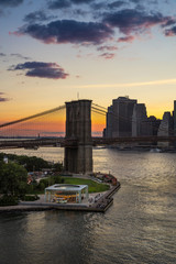 Fototapete - Sunset over the Brooklyn Bridge and Carousel with view on the Manhattan Lower East Side Financial District. East River. New York City