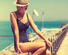 Young Woman In Swimsuit And Sun Hat. 
Girl In A Straw Hat , Bikini And Sunglasses Sunbathing On The Beach In Europe .