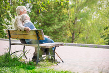 Elderly Couple Resting On A Bench In The Park