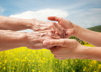 Wall Mural - Hands of an elderly senior holding the hand of a woman