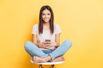 Wall Mural - Woman sitting on the chair and using smartphone