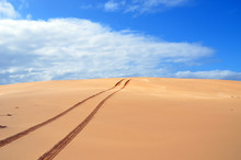 Tracks In Remote Sand Dunes Under Blue Skies