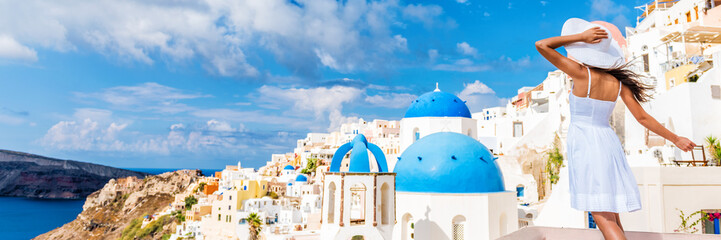 Fototapete - Europe tourist travel woman panorama banner from Oia, Santorini, Greece. Happy young woman looking at famous blue dome church landmark destination. Beautiful girl visiting the Greek islands.