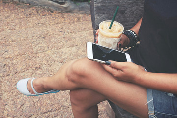 Canvas Print - Woman using smart phone with iced coffee