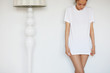 Close up shot of young female model posing against home interior, wearing white blank loose copy space T-shirt of her boyfriend while staying at his place for the weekend. People and lifestyle concept