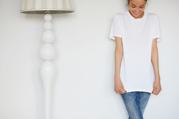 Human face expressions and emotions. Cropped portrait of attractive young female with happy smile posing in white blank copy space T-shirt for your advertising content against white studio wall.