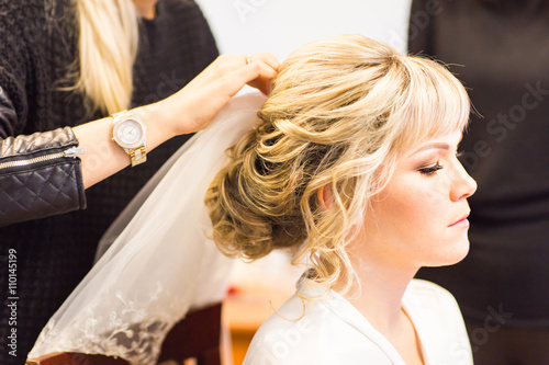 Obraz na plátně Hair stylist makes the bride before a wedding