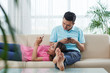 © DragonImages - Young Asian couple resting on sofa and using apps