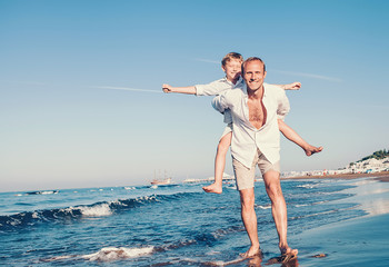 Wall Mural - Happy son and father play together on the sea surf