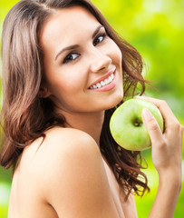 Young happy smiling woman with apple, outdoors