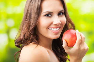 Young happy smiling woman with apple, outdoors