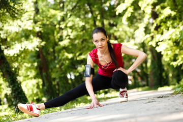 Young sportswoman stretching and preparing to run in park.