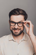 © deagreez - Portrait of attractive happy young man in glasses on gray backgr