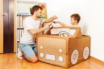 Father and his son making toy car of cardboard box