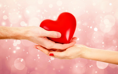 Poster - Female and male hands holding red heart on blurred background. Family, love and health care concept