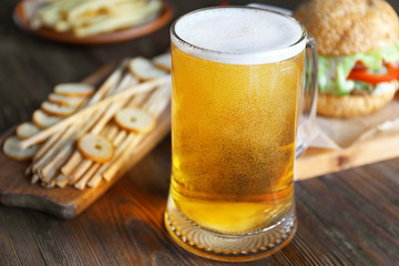 Wall Mural - Glass mug of light beer with snacks on dark wooden table, close up