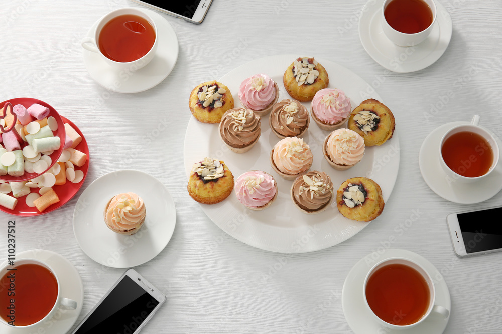 Tea Party with sweet creamy cakes over wooden table background
