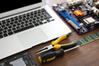 Laptop and Different electronic circuits, tools on wooden background