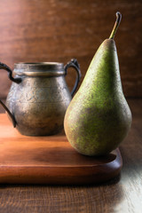 Pear and bronze dish on wooden cutting board