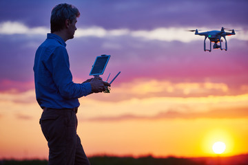 Wall Mural - man operating of flying drone at sunset