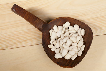 Wall Mural - close-up shot of white beans in wooden spoon.