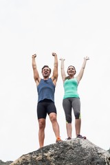 Wall Mural - Cheerful young couple on rock against sky