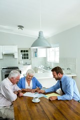 Senior couple with agent while sitting at table 