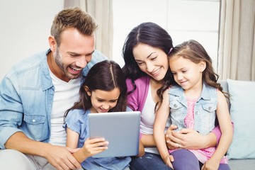 Wall Mural - Family smiling while looking in digital tablet