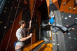 © anatoliy_gleb - Belayer holding a rope with special equipment belaying the climber on rock wall indoors