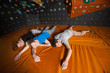 © anatoliy_gleb - Three tired climbers with closed eyes lying on the orange mat near rock wall indoors. Bouldering