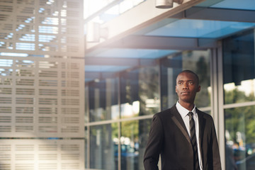 Optimistic young African businessman with office building and flare