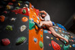 © anatoliy_gleb - Male rock climber practicing artificial rock climbing on a rock wall indoors, with climbing shoes. Bouldering